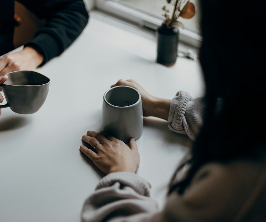 Two people talking at a table over cups of coffee