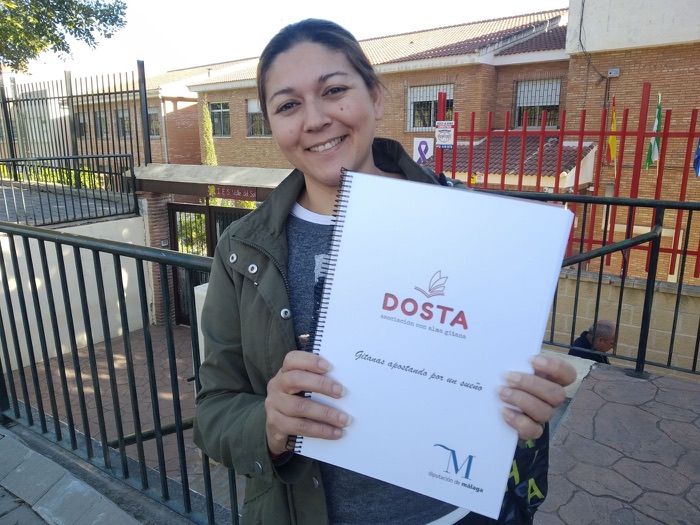 A smiling woman showing her notebook from the «Gitanas apostando por un sueño» programme
