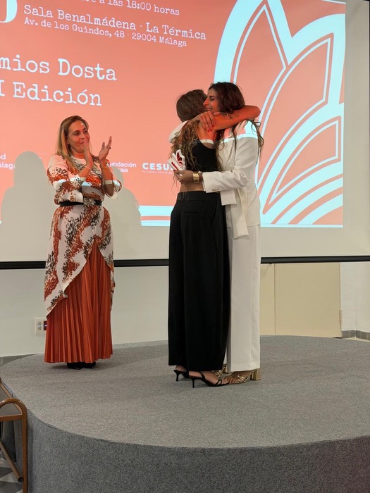 Two women hug on stage at the Dosta Awards
