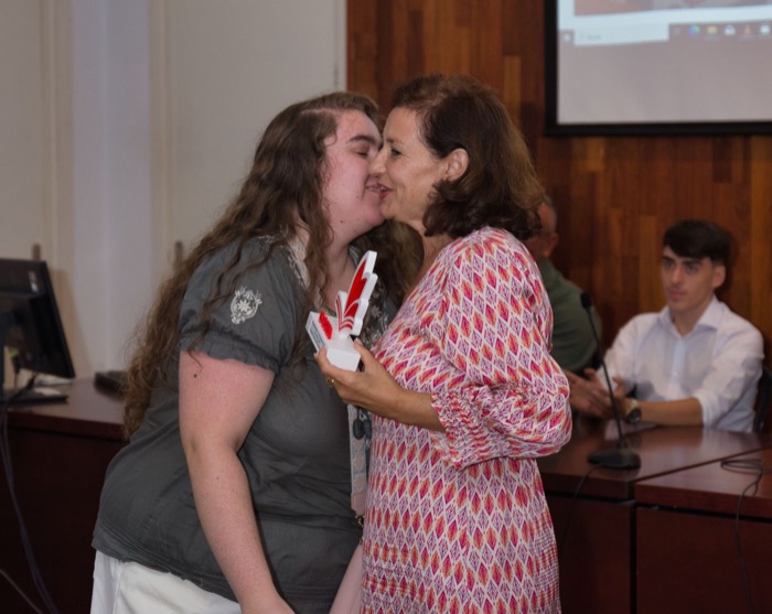 An award winner, trophy in hand, receives an emotional kiss
