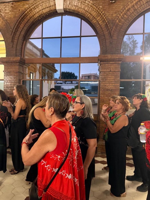 Women hugging at the Dosta Awards reception, one wearing a red shawl