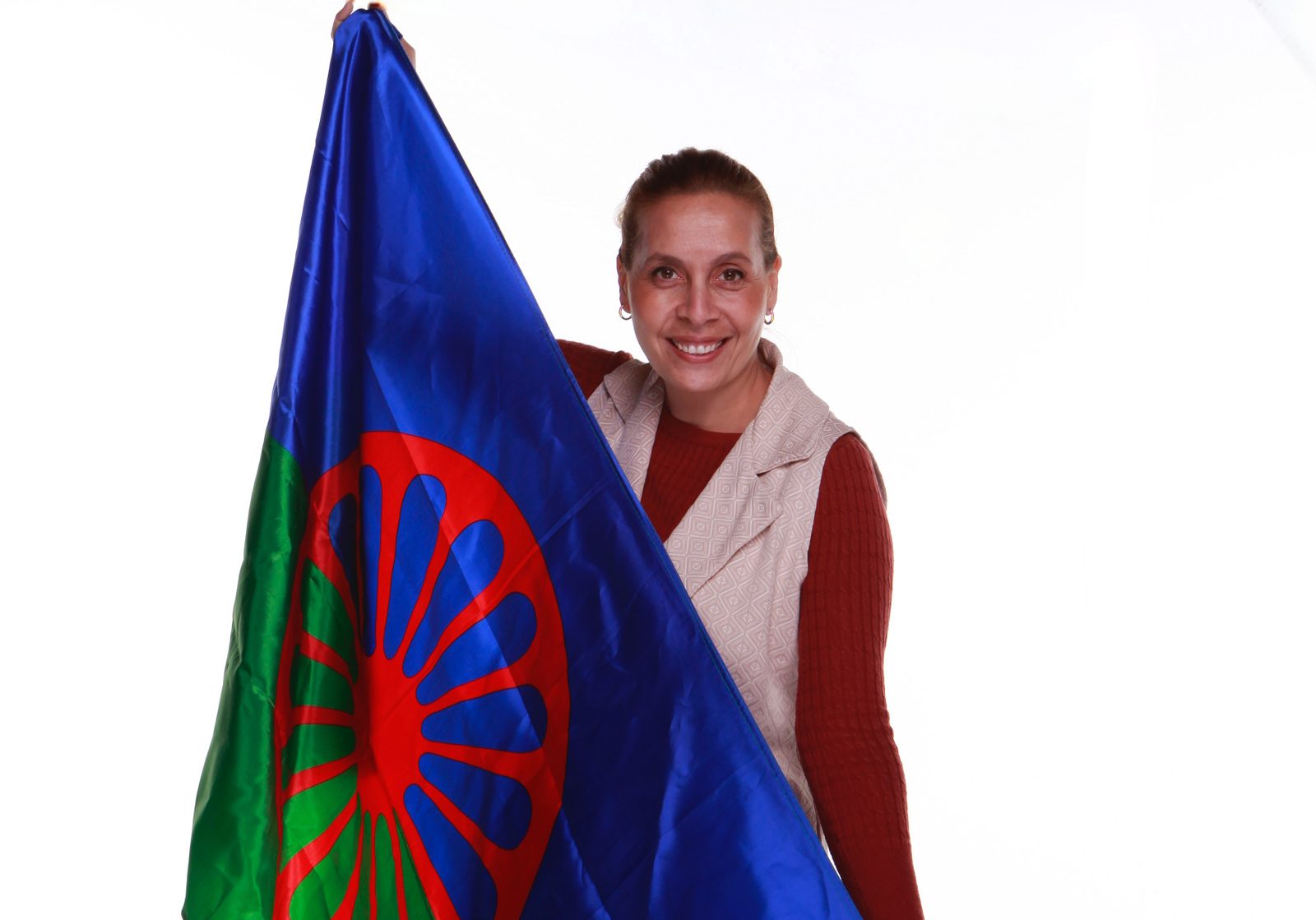 A smiling Romani woman holding the Romani flag